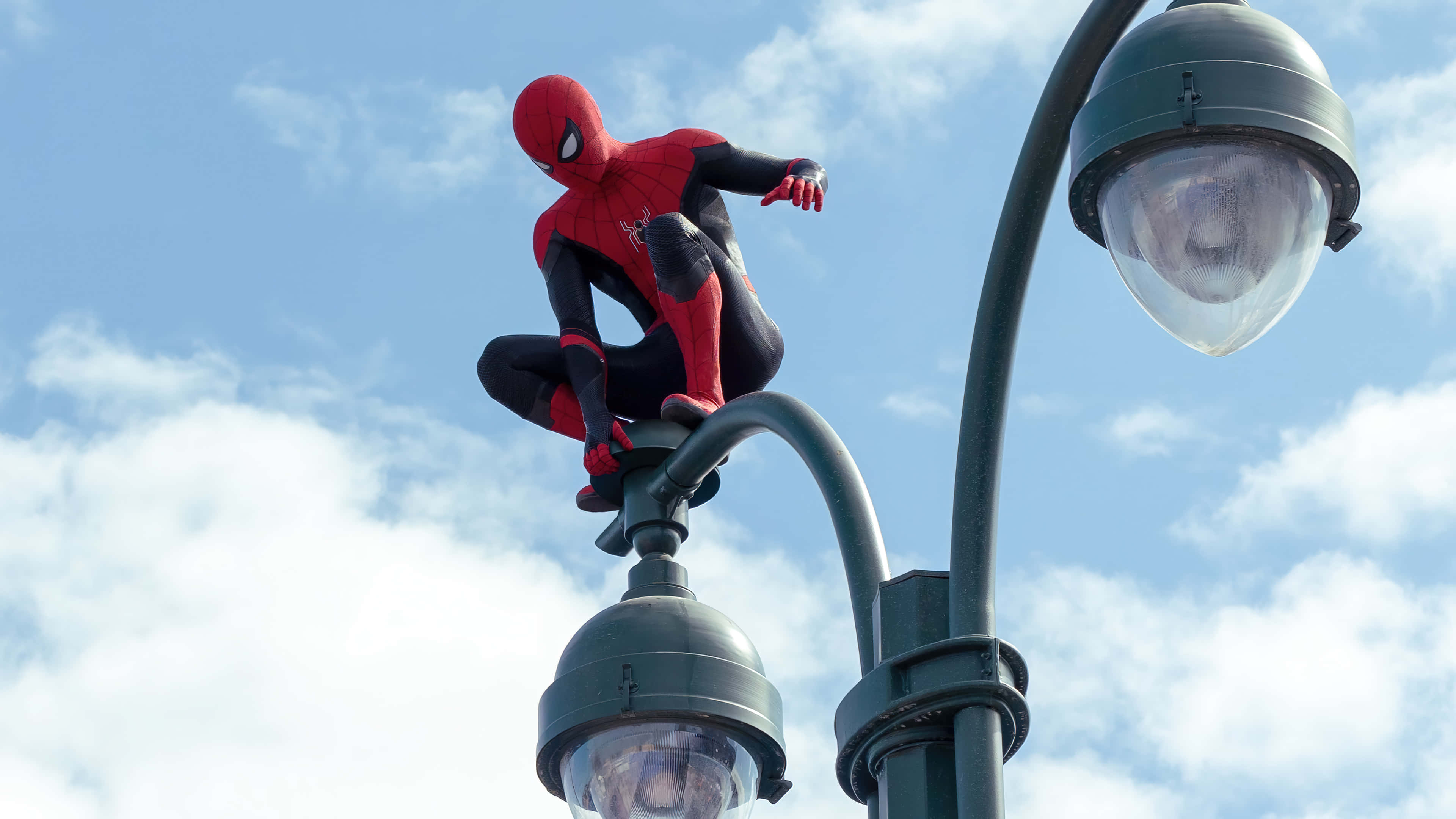 Spider Man No Way Home 桌布 壁紙 — 蜘蛛俠蹲在街燈頂上，背景是明亮的藍天和蓬鬆的白雲。