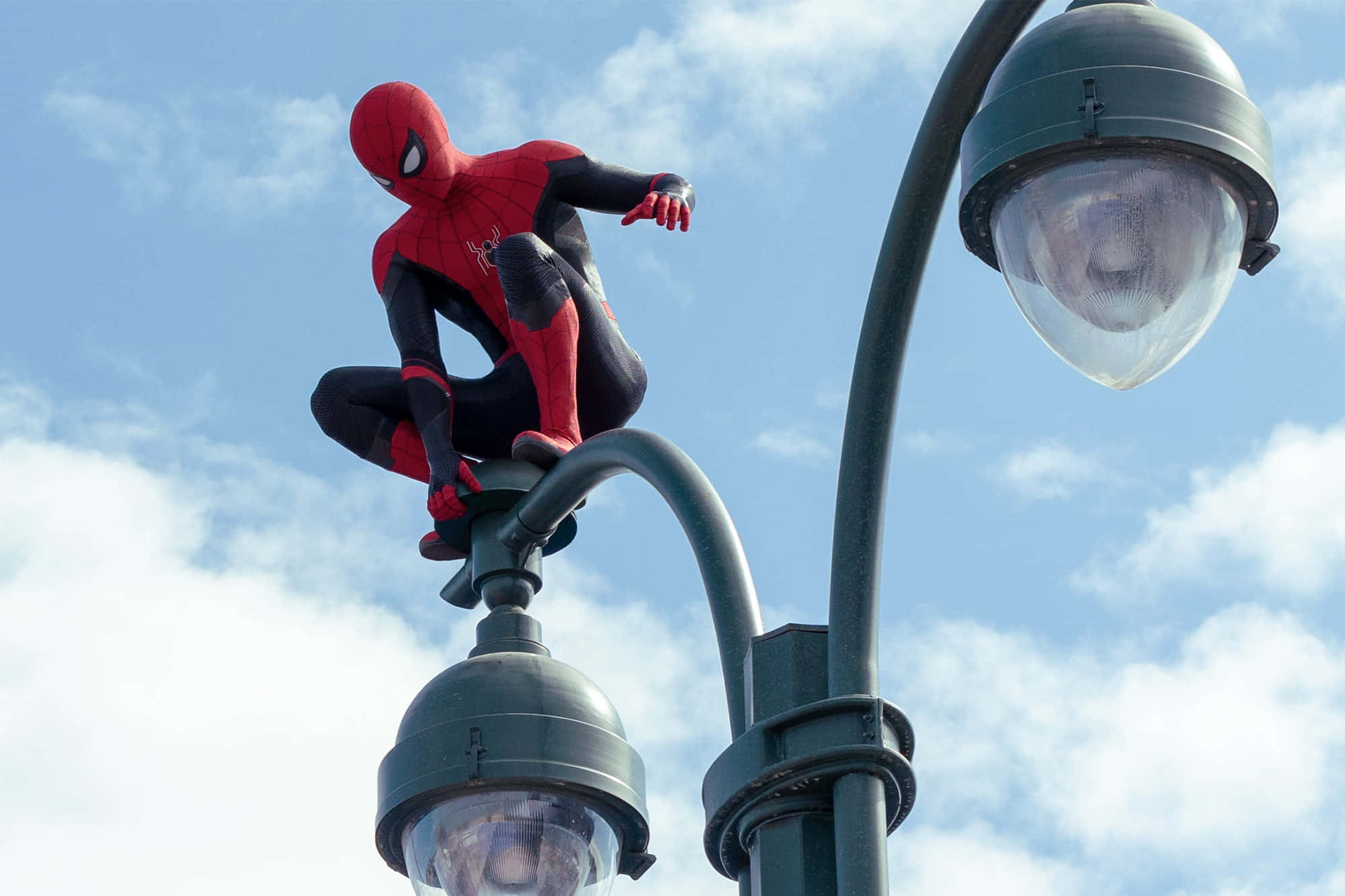 Spider Man No Way Home 桌布 壁紙 — 蜘蛛俠蹲在街燈頂上，背景是明亮的藍天和蓬鬆的白雲。
