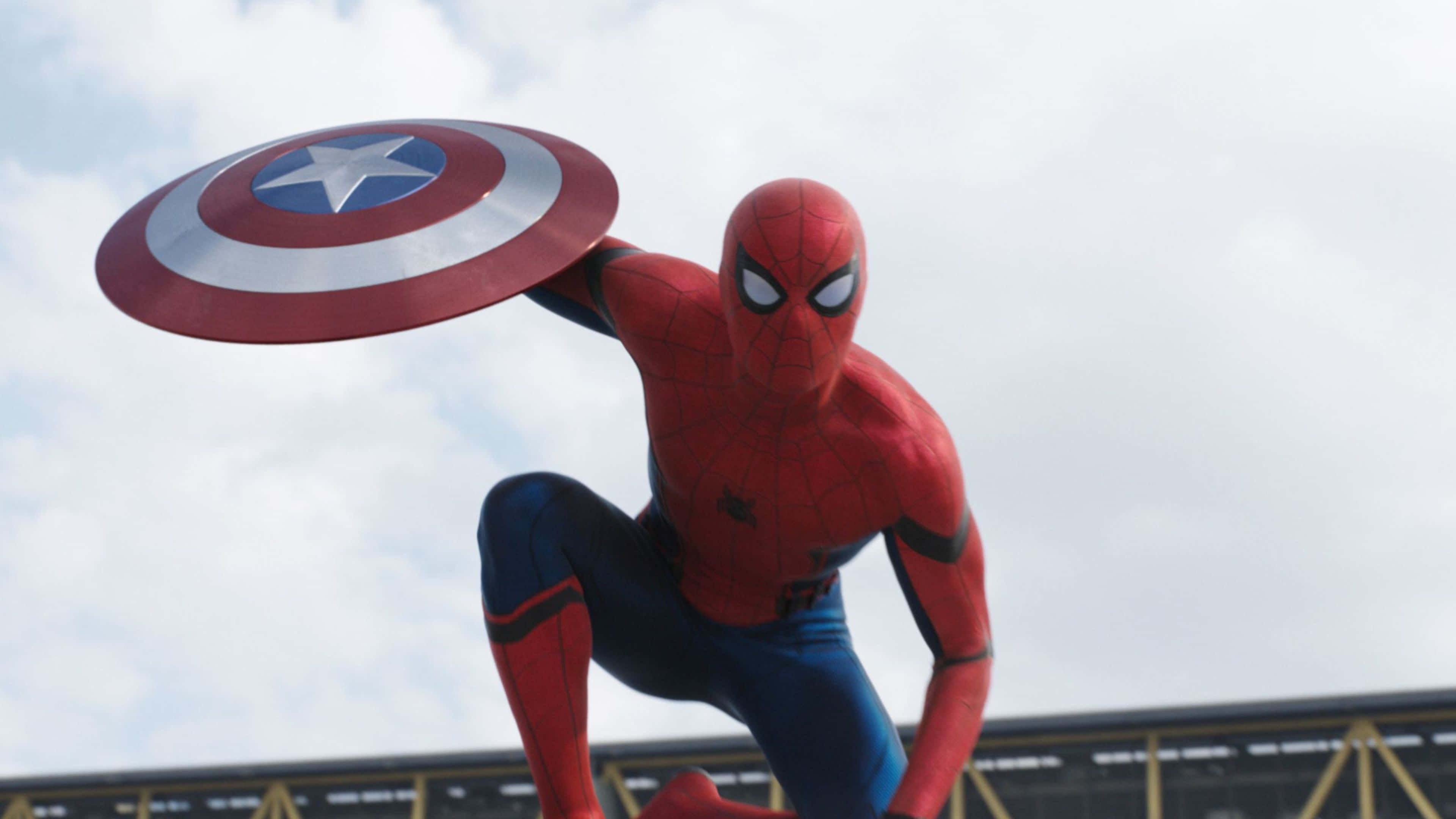 4K Captain America 桌布 壁紙 — 蜘蛛俠身穿紅藍戰衣，動態地蹲下，手持美國隊長的盾牌，背景是陰天。