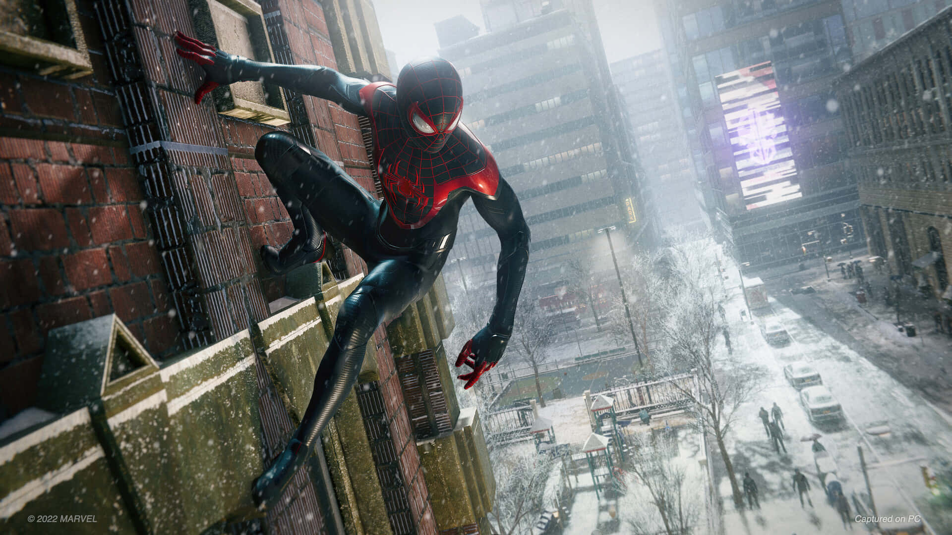 Miles Morales 動漫 桌布 壁紙 — 蜘蛛俠身穿紅黑色戰衣，在積雪覆蓋的城市建築之間擺盪，構成冬日都市場景。