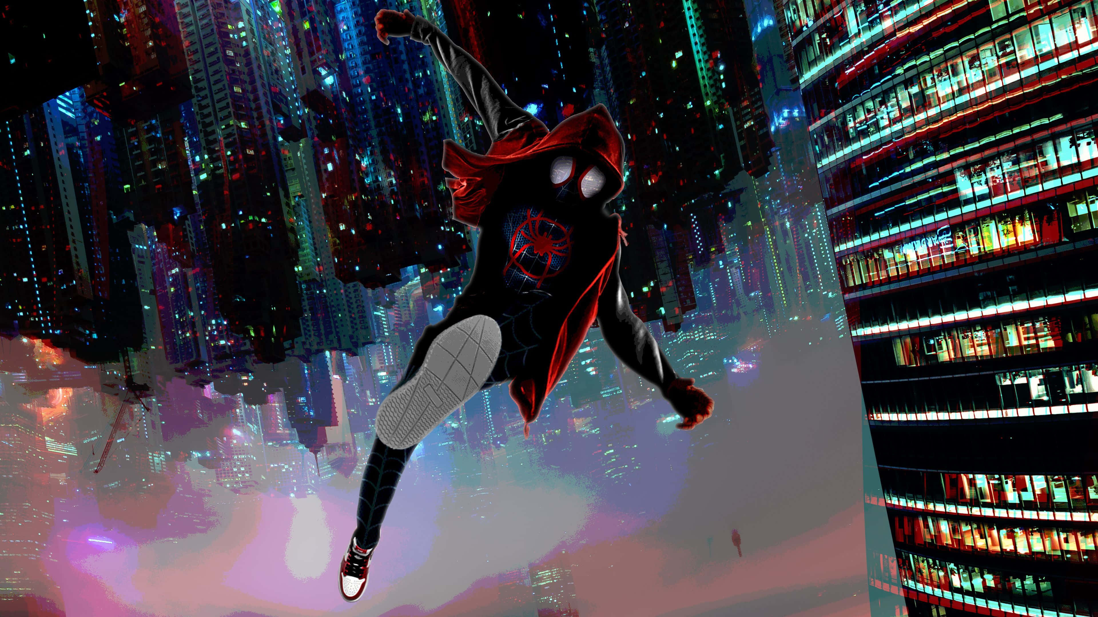 Miles Morales 動漫 桌布 壁紙 — 蜘蛛俠身穿黑色戰衣配紅色斗篷，在夜晚霓虹燈閃爍的未來城市景觀中動態擺盪。