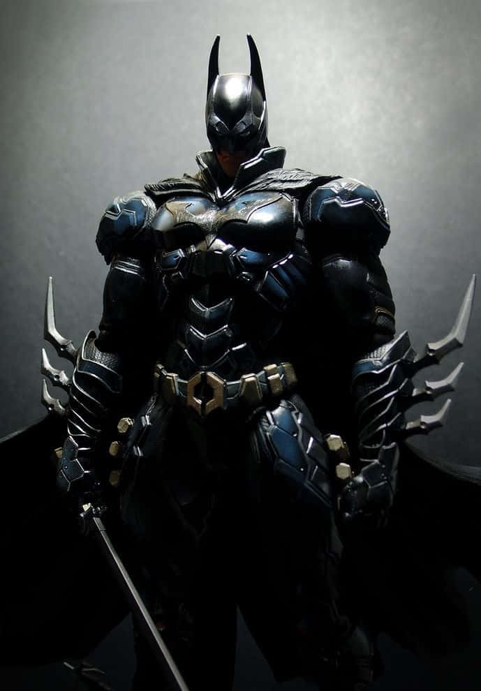 Batman Knightfall 桌布 壁紙 — 蝙蝠俠以戲劇性的剪影站在深灰色背景前，他的裝甲服在聚焦燈光下閃閃發光。