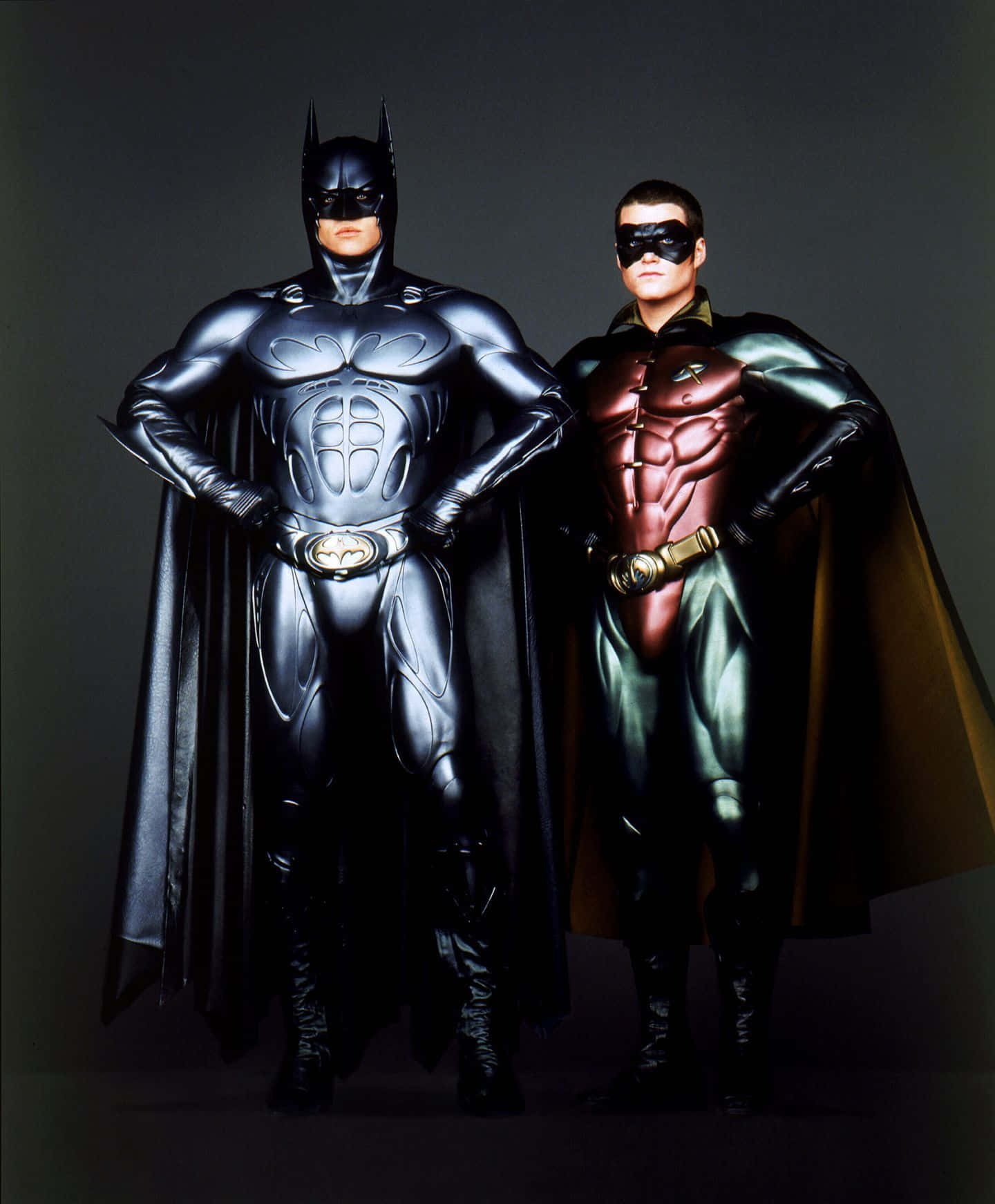 Batman Vs Robin 桌布 壁紙 — 蝙蝠俠和羅賓自信地站在黑暗的攝影棚背景下，身穿閃亮的裝甲服裝。