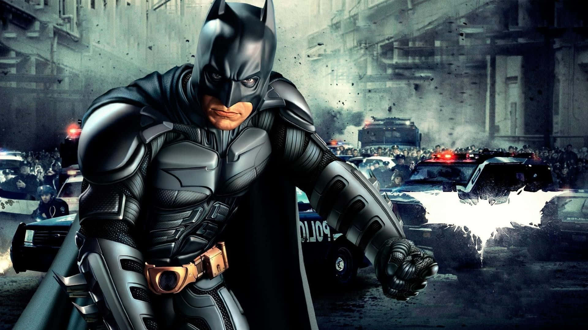 Batman Desktop 桌布 壁紙 — 蝙蝠俠在雨濕的葛咸城街道上挑釁地站立，警車和人群在他身後混亂地湧動。