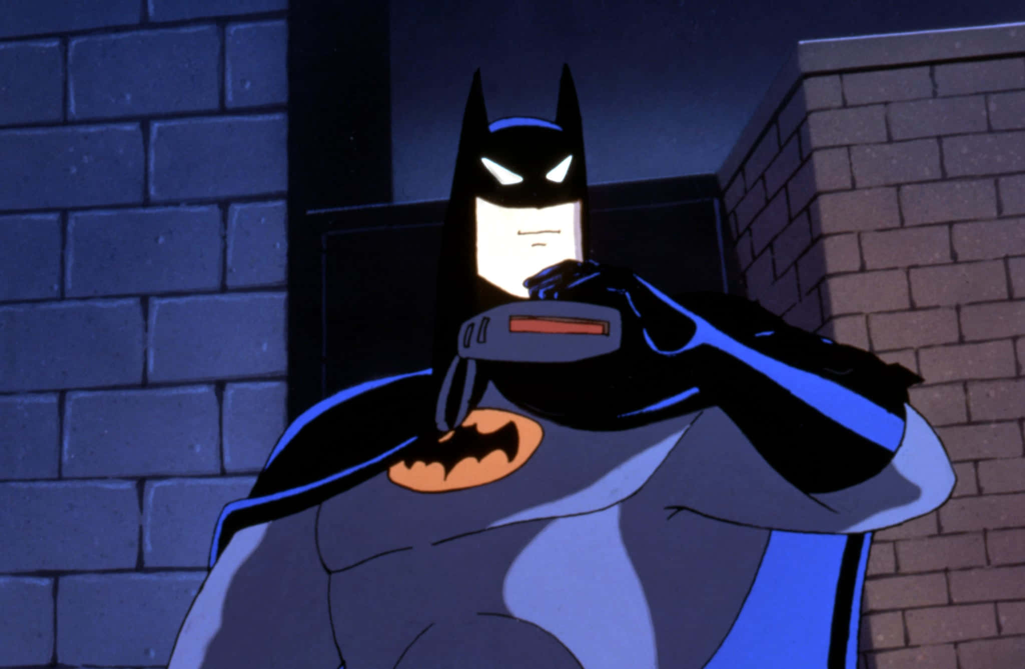 Batman Mask Of The Phantasm 桌布 壁紙 — 蝙蝠俠夜晚站在黑暗的小巷中，將一個裝置放在下巴下靠著磚牆。