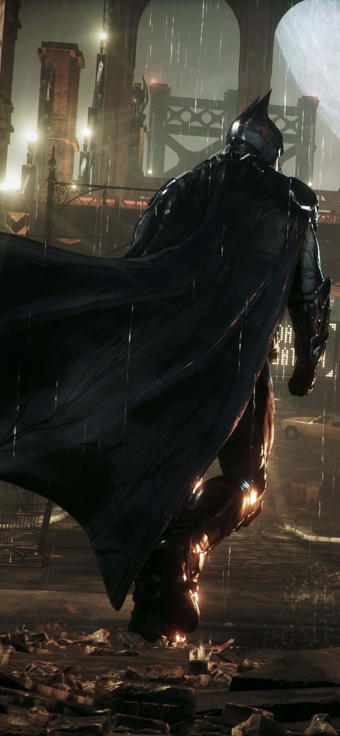 Batman Arkham Knight 桌布 壁紙 — 蝙蝠俠站在夜間雨淋濕的哥譚小巷中，斗篷飄揚，霓虹燈光反射在潮濕的瀝青和破碎的碎片上。