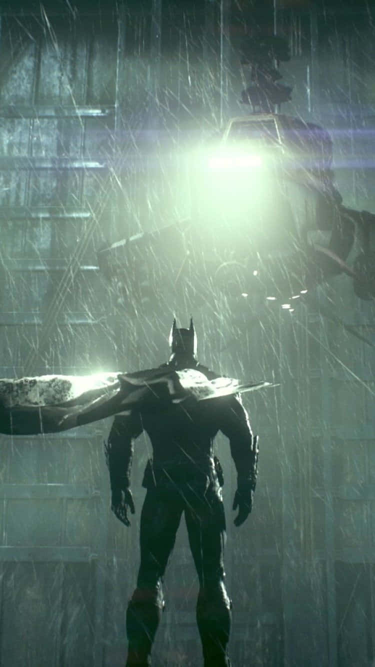 Batman Arkham Knight 桌布 壁紙 — 蝙蝠俠站在被雨水浸濕的城市小巷中，一架懸浮車輛的明亮燈光照亮了他的剪影。