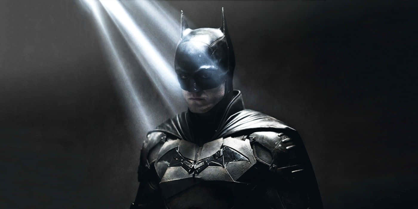 Bruce Wayne 桌布 壁紙 — 蝙蝠俠站在陰影中，戲劇性的光束穿過煙霧，突顯他的裝甲服和堅定的目光。
