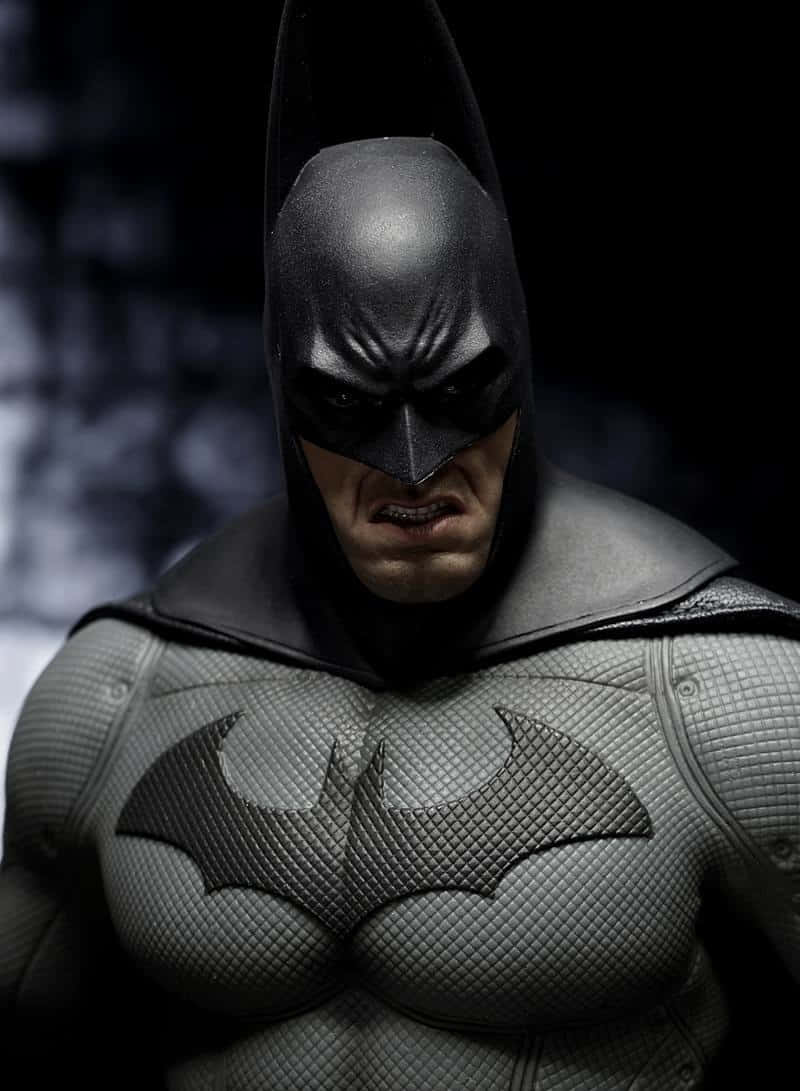 Arkham Asylum 桌布 壁紙 — 蝙蝠俠身穿質感裝甲服的特寫，在黑暗模糊的背景中露出嚴峻的表情。