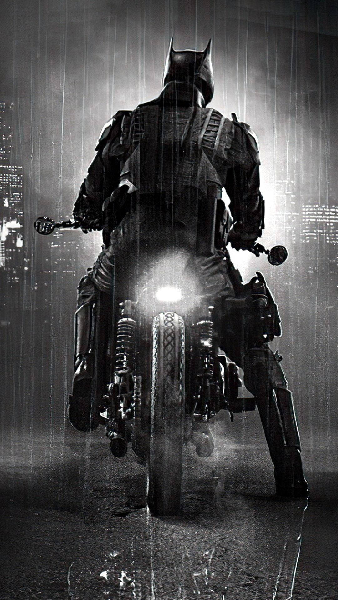 蝙蝠俠騎乘蝙蝠車摩托 壁紙 — 蝙蝠俠在雨水浸濕的城市街道上騎電單車，車頭燈刺破黑暗。