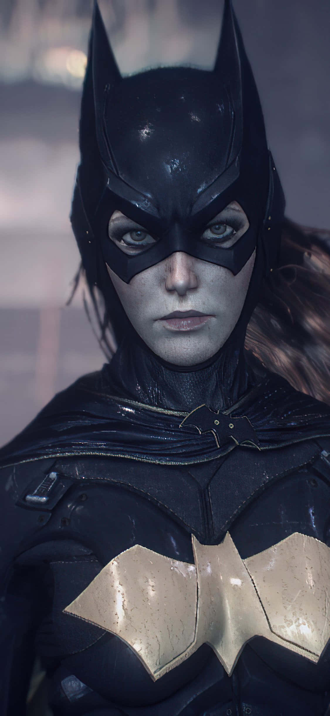 Batman Arkham Knight 桌布 壁紙 — 蝙蝠女近距離特寫，身穿深色裝甲服，胸前有金色蝙蝠標誌，在模糊的城市背景下凝視著。