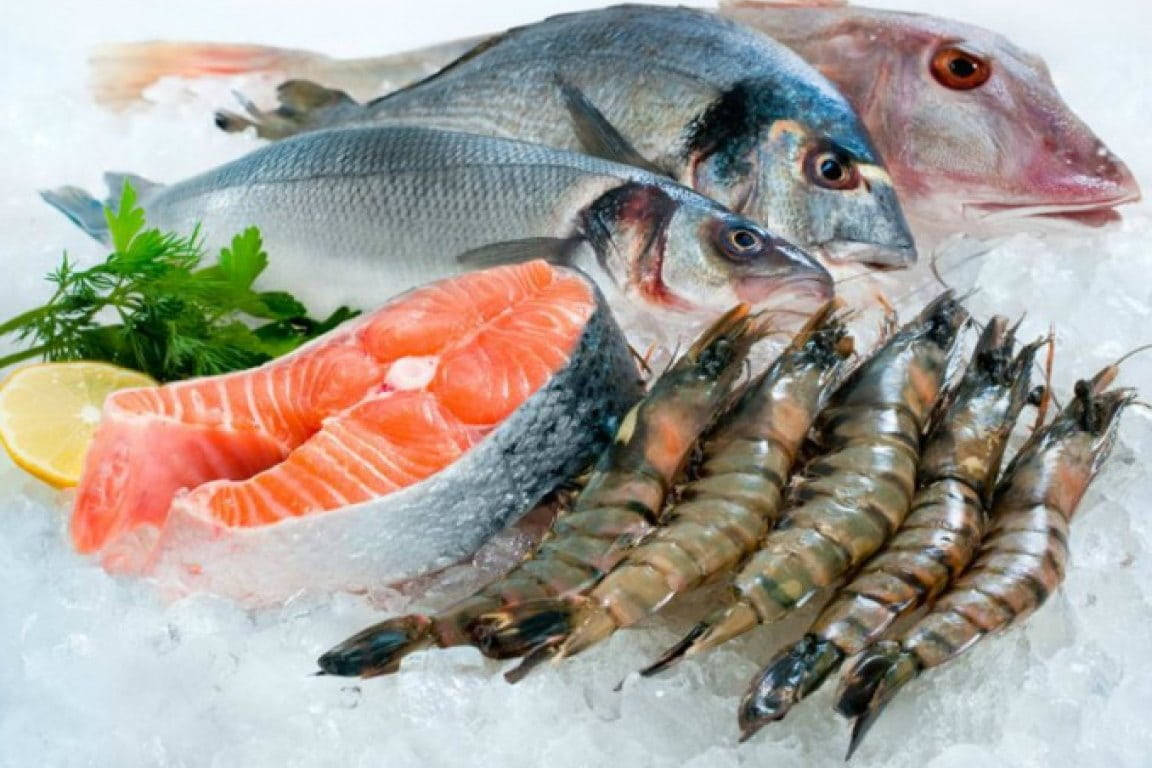 新鮮海鮮展示，有魚、蝦和三文魚柳放在冰上，以檸檬和歐芹裝飾。