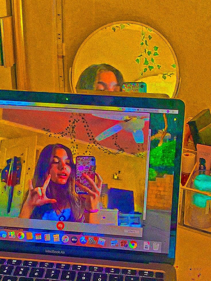 在裝飾過的房間裏，手提電腦屏幕上有人在鏡子和藤蔓旁自拍。