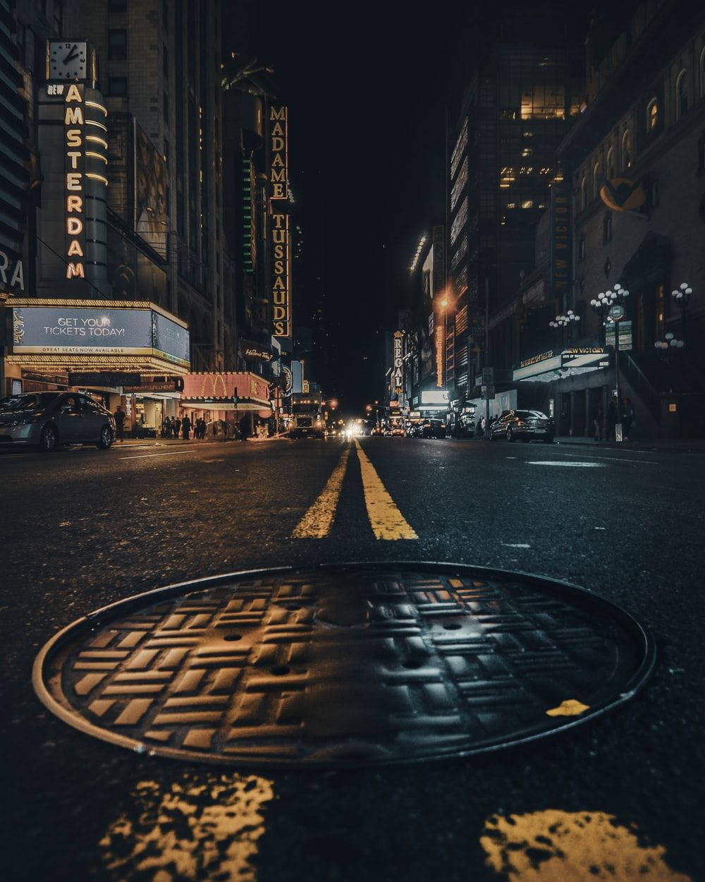 夜間城市街道，閃爍霓虹招牌，前景有沙井蓋。