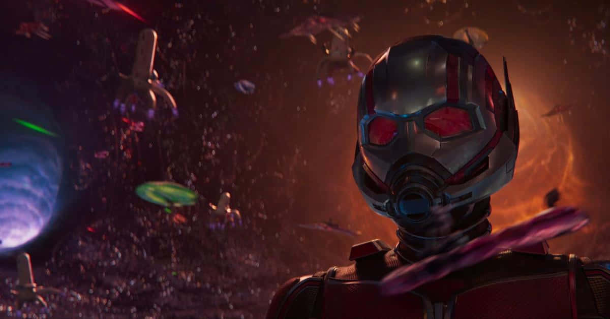 Quantum Realm 桌布 壁紙 — 蟻人穿着戰衣站在宇宙碎片中，背景有發光的行星和漂浮的太空船。