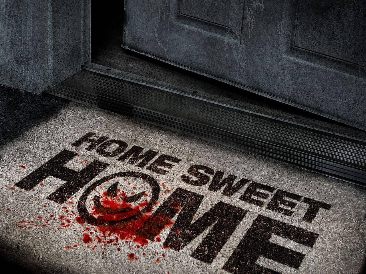 血腥「家是甜蜜的家」門墊 壁紙 — 一個陰森嘅門墊，上面有「HOME SWEET HOME」字樣，喺黑暗門口附近濺滿血跡。