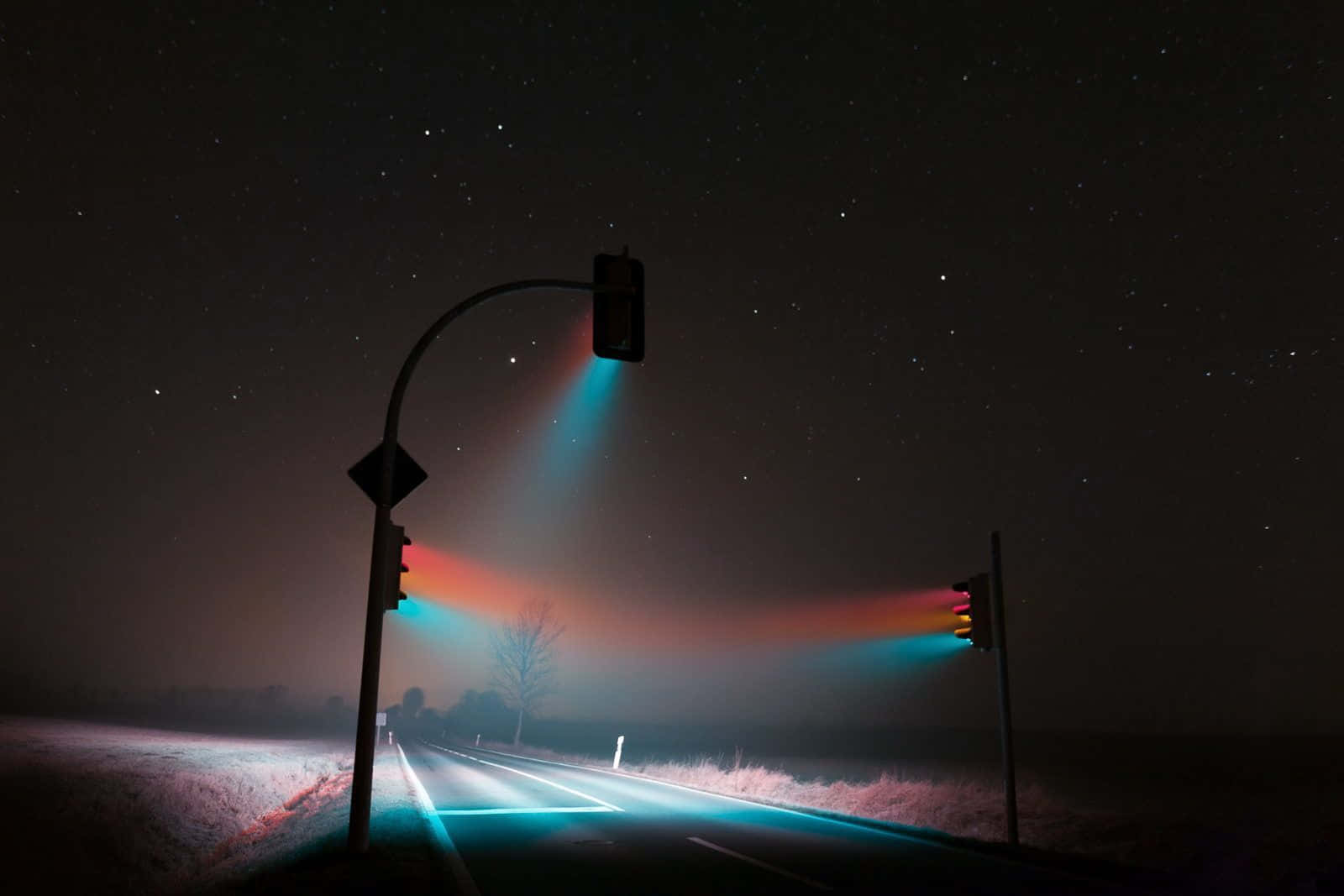 星空下，霧中帶有發光交通燈的夜路