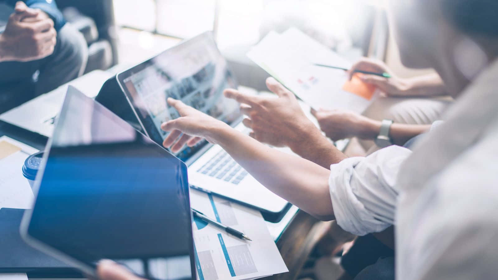 Team of professionals working together with laptops and papers in a modern office.
