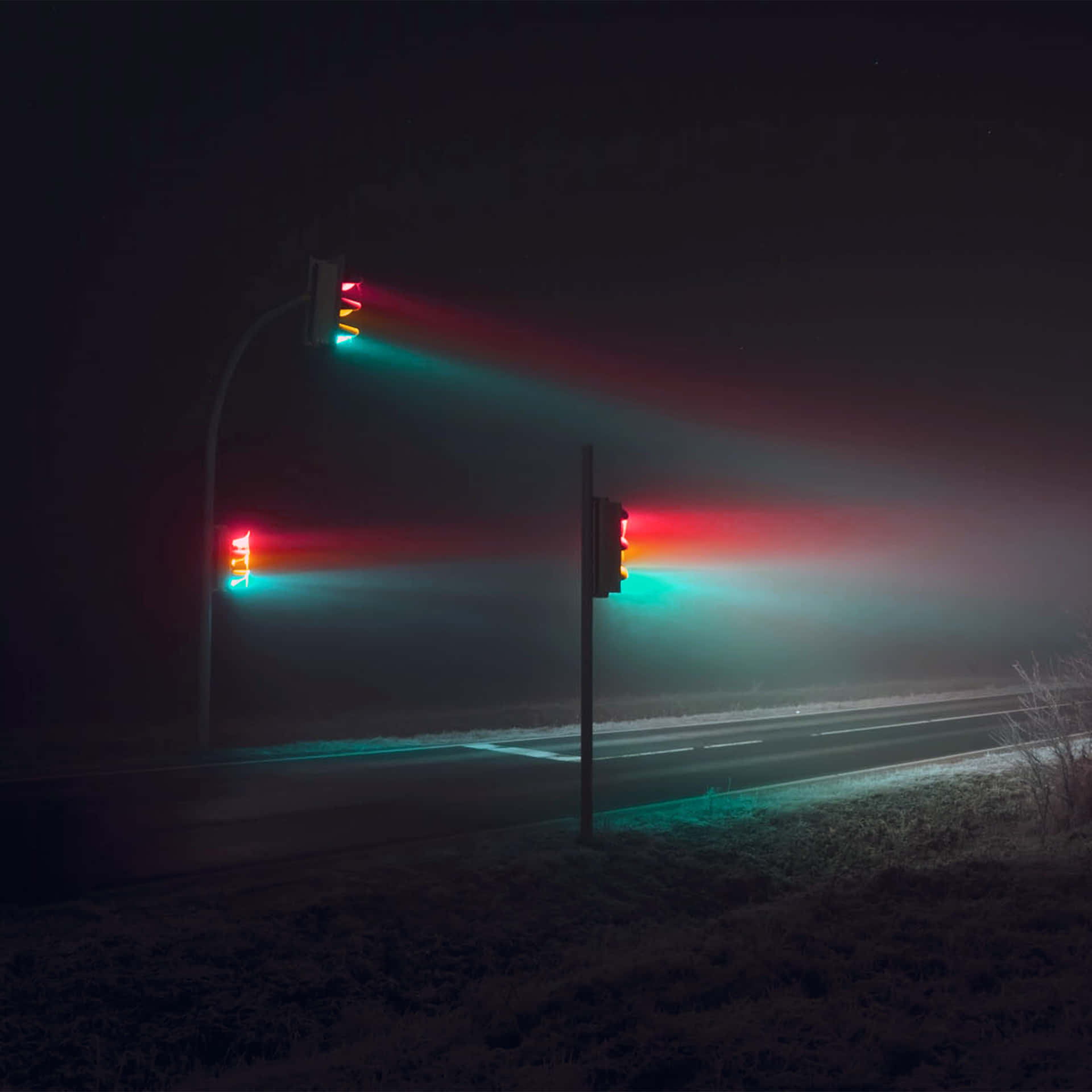 霧夜中道路上發出紅綠光芒的交通燈