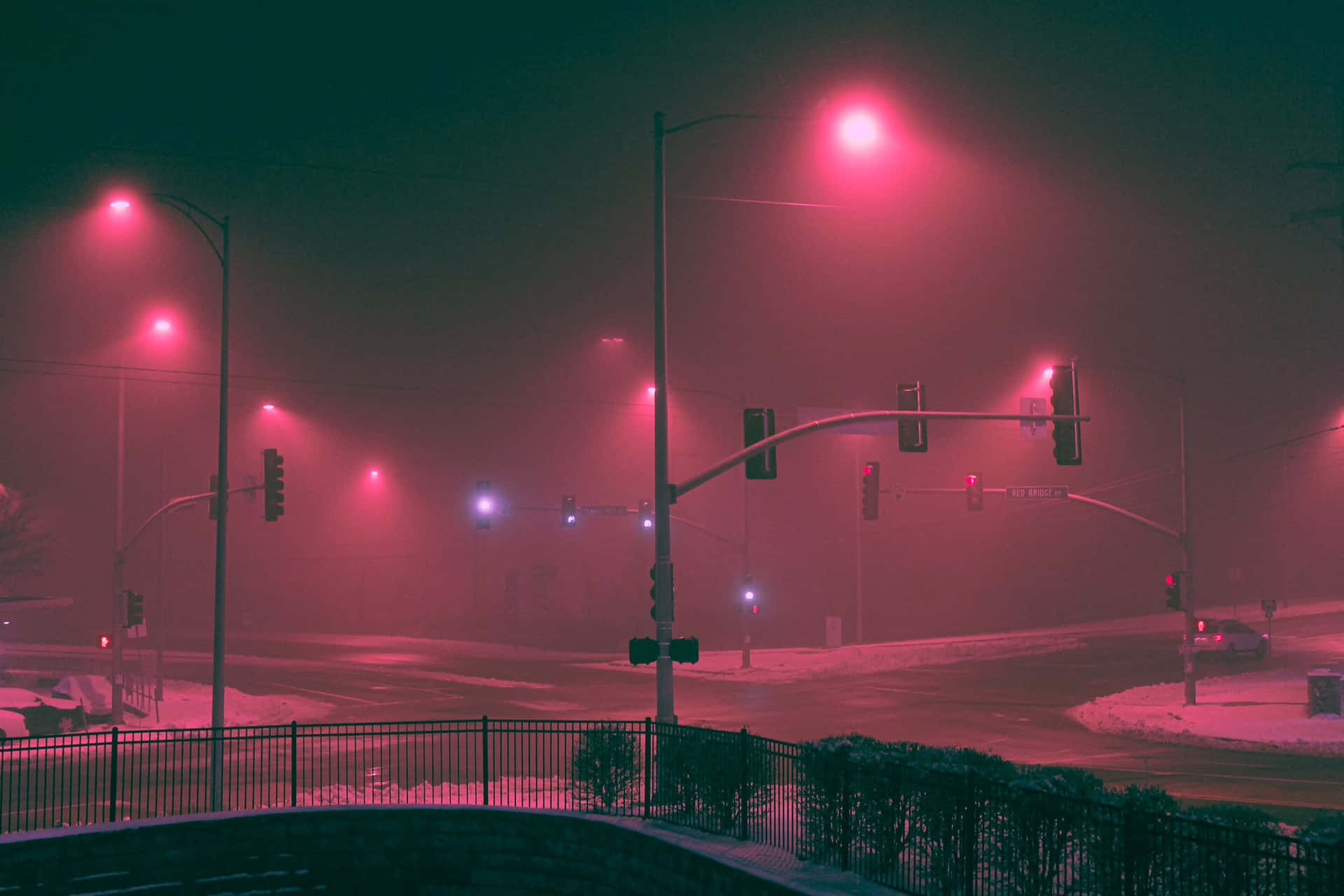 夜晚紅色燈光照亮的積雪街道十字路口，有霧和交通燈。