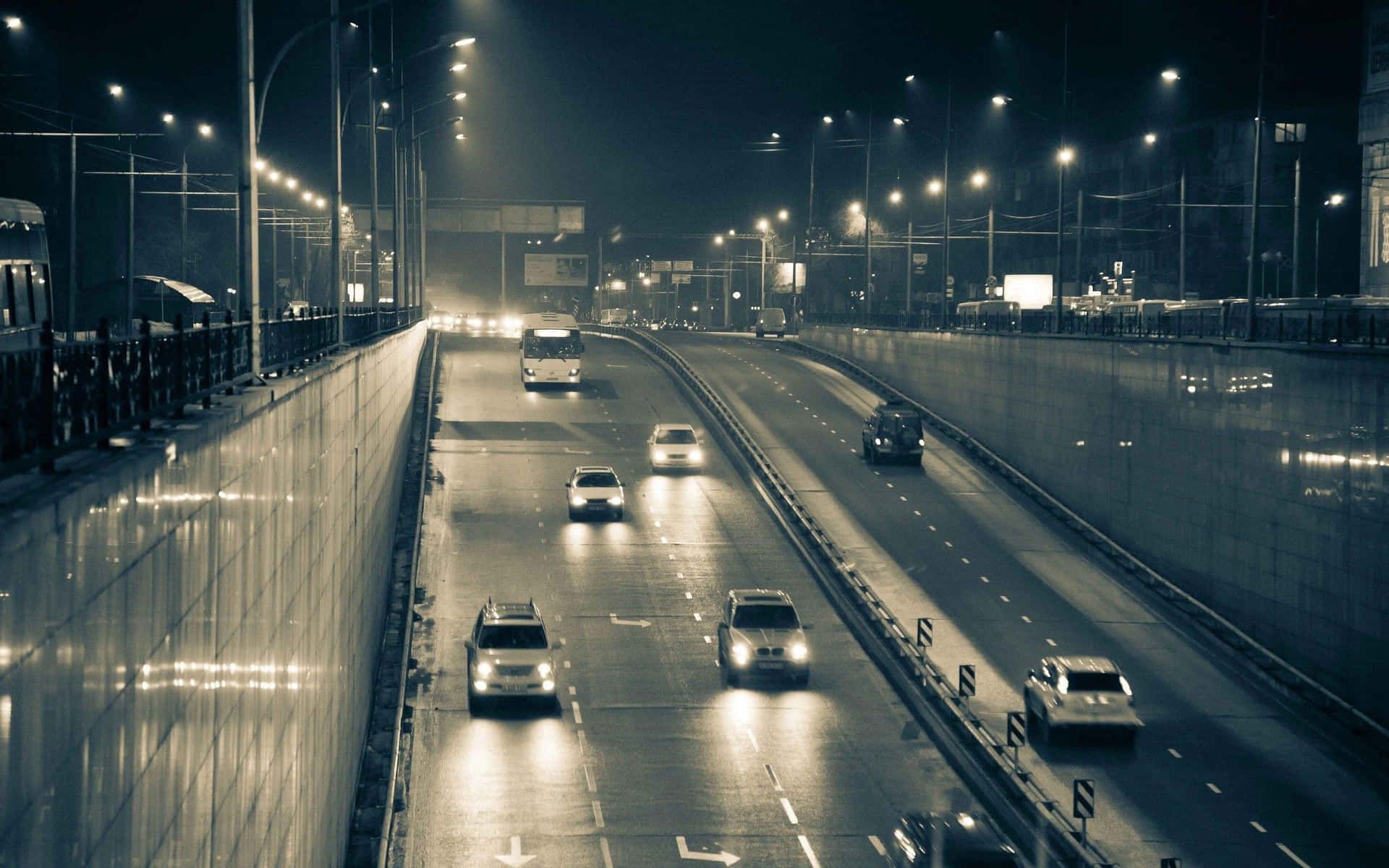 夜間高速公路，汽車和街燈反射在濕漉漉的路面上。