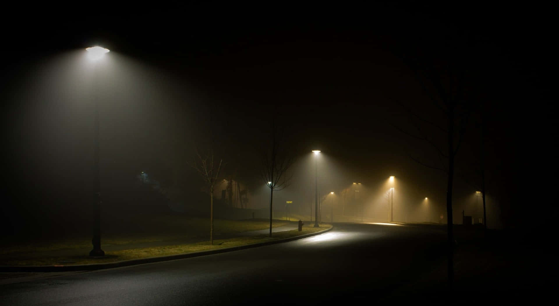 霧氣瀰漫的城市夜晚街道，被發光的路燈照亮。