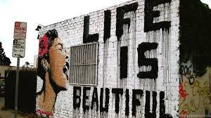 磚牆上的塗鴉壁畫，帶有文字 life is beautiful 和花卉肖像
