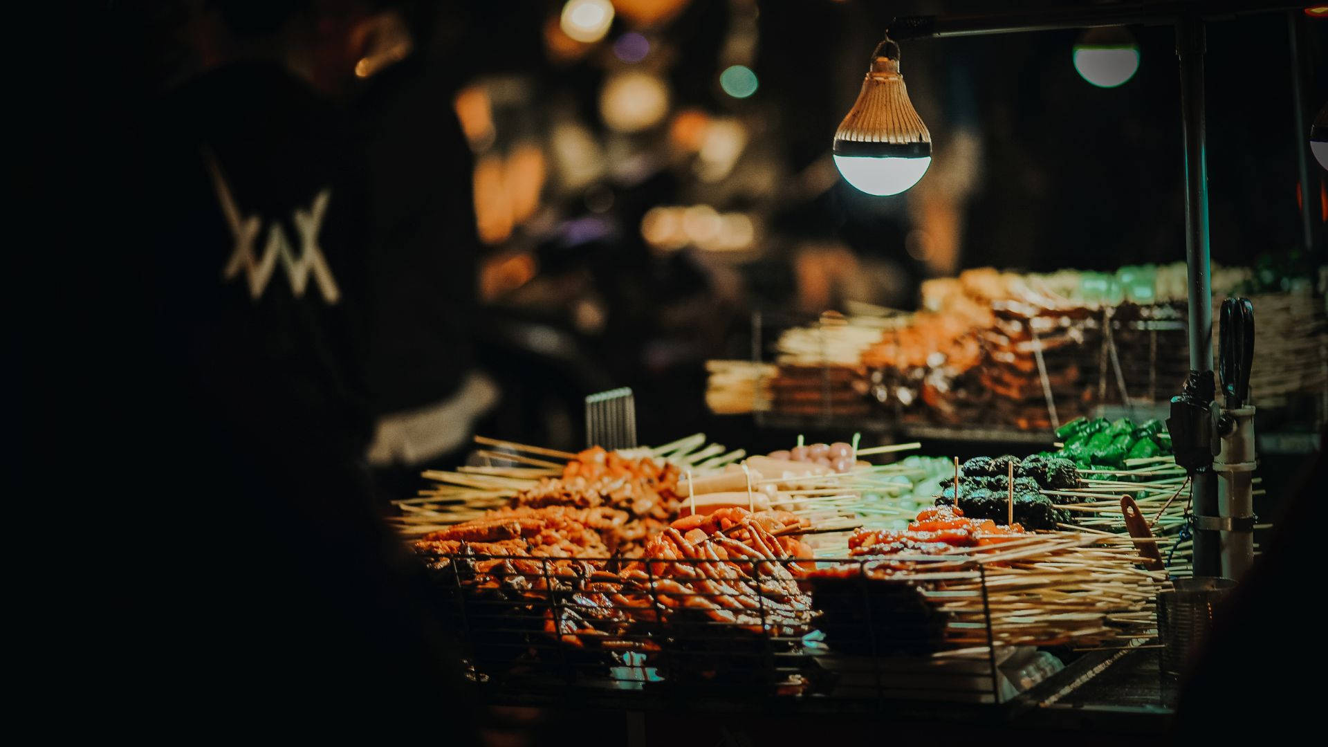 夜市攤位上發光燈泡下的烤肉串。