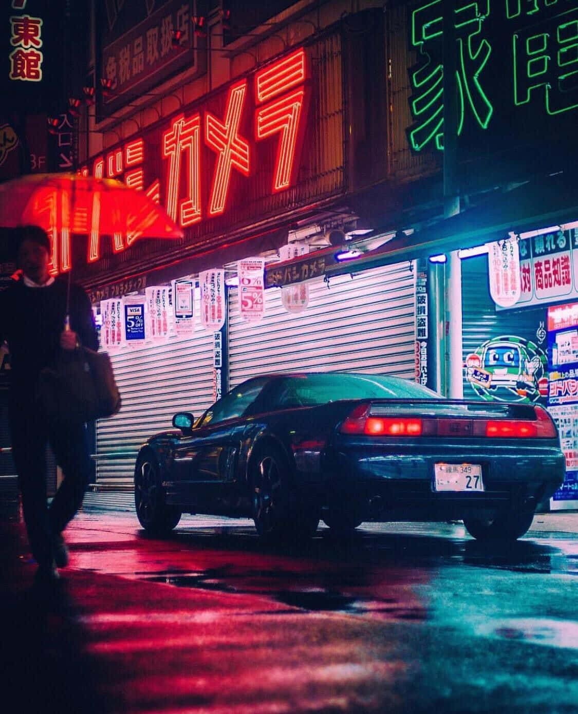 撐紅傘的人走過停在霓虹燈下、雨夜街頭的跑車。