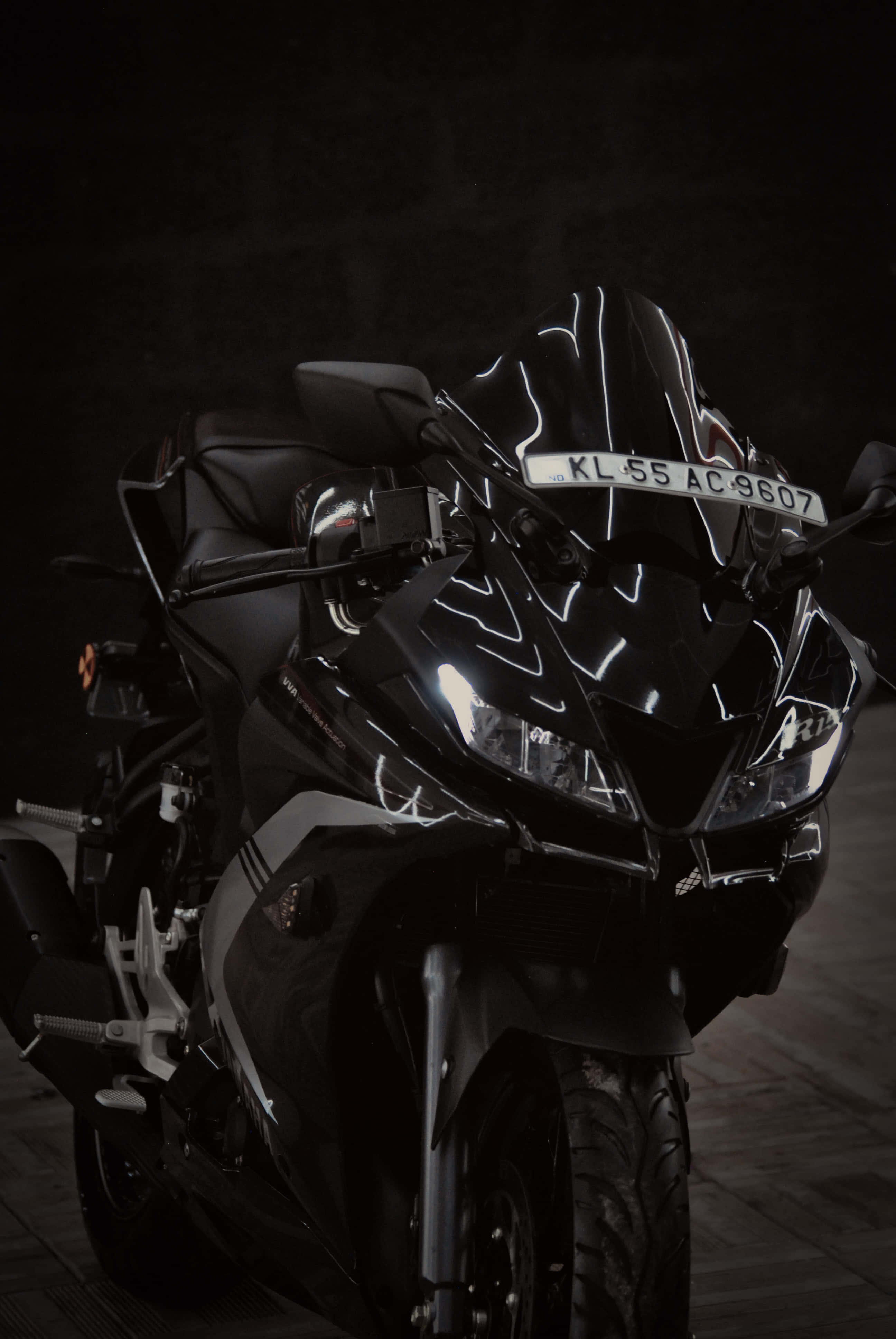 衝向新高度 — Yamaha R15 v3 壁紙 — 一輛時尚的黑色運動電單車在戲劇性的影樓燈光下，在深色紋理背景上閃閃發光。