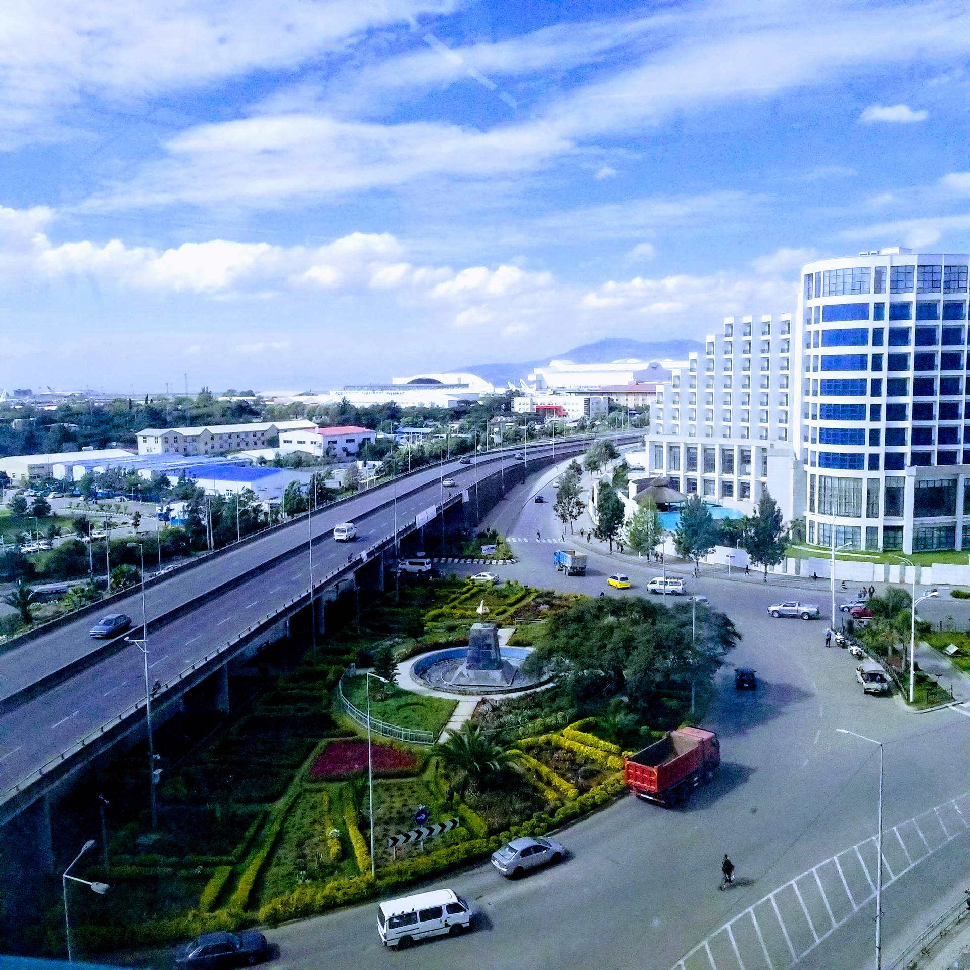 現代城市的鳥瞰圖，有高速公路、環島和玻璃建築，在藍天下。