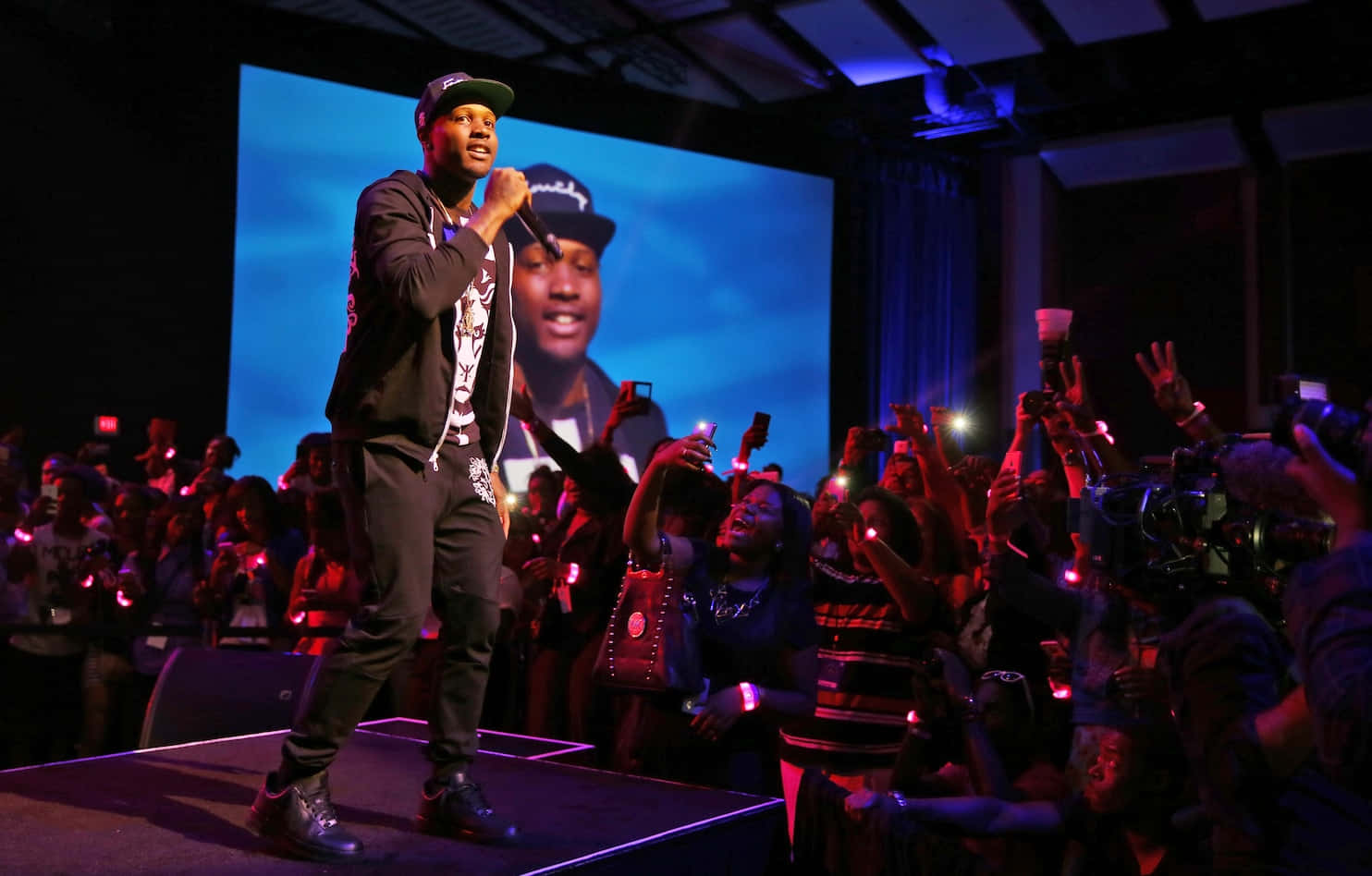 lil durk 桌布 壁紙 — 表演者在藍色燈光下為舞台上的觀眾注入活力，粉絲們舉起發光的手機。