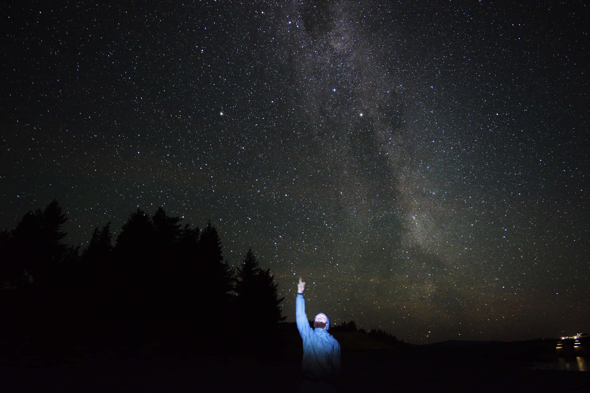 人在森林附近的星空下指向銀河