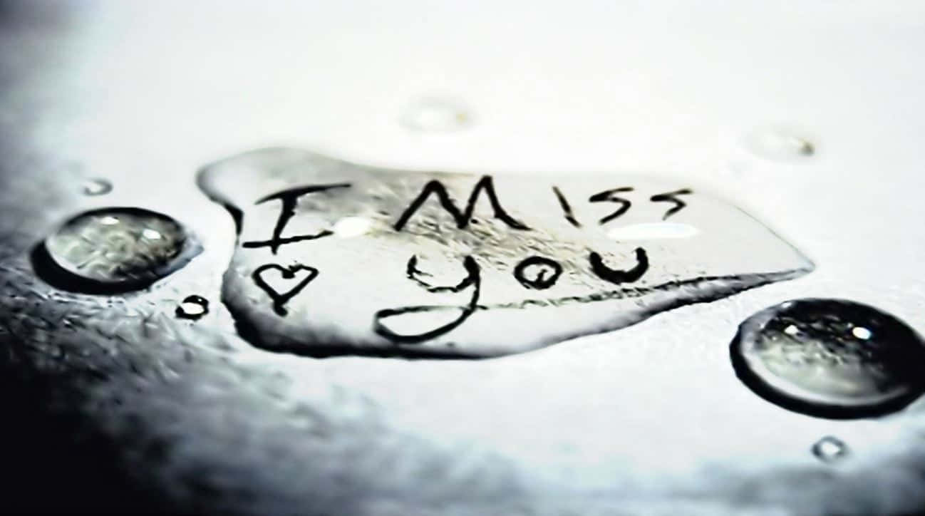 I Miss You 桌布 壁紙 — 表面上的一滴眼淚揭示了手寫訊息「我想你」，周圍環繞著閃閃發光的水滴。