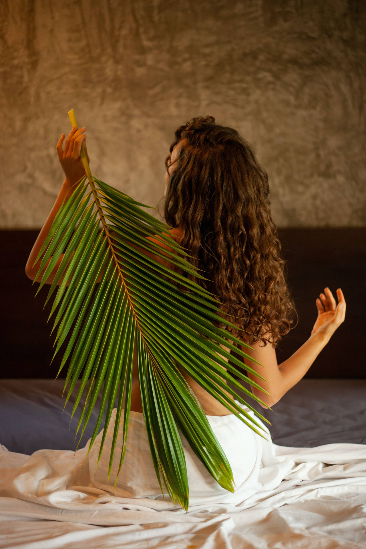 女性在床上手持棕櫚葉室內