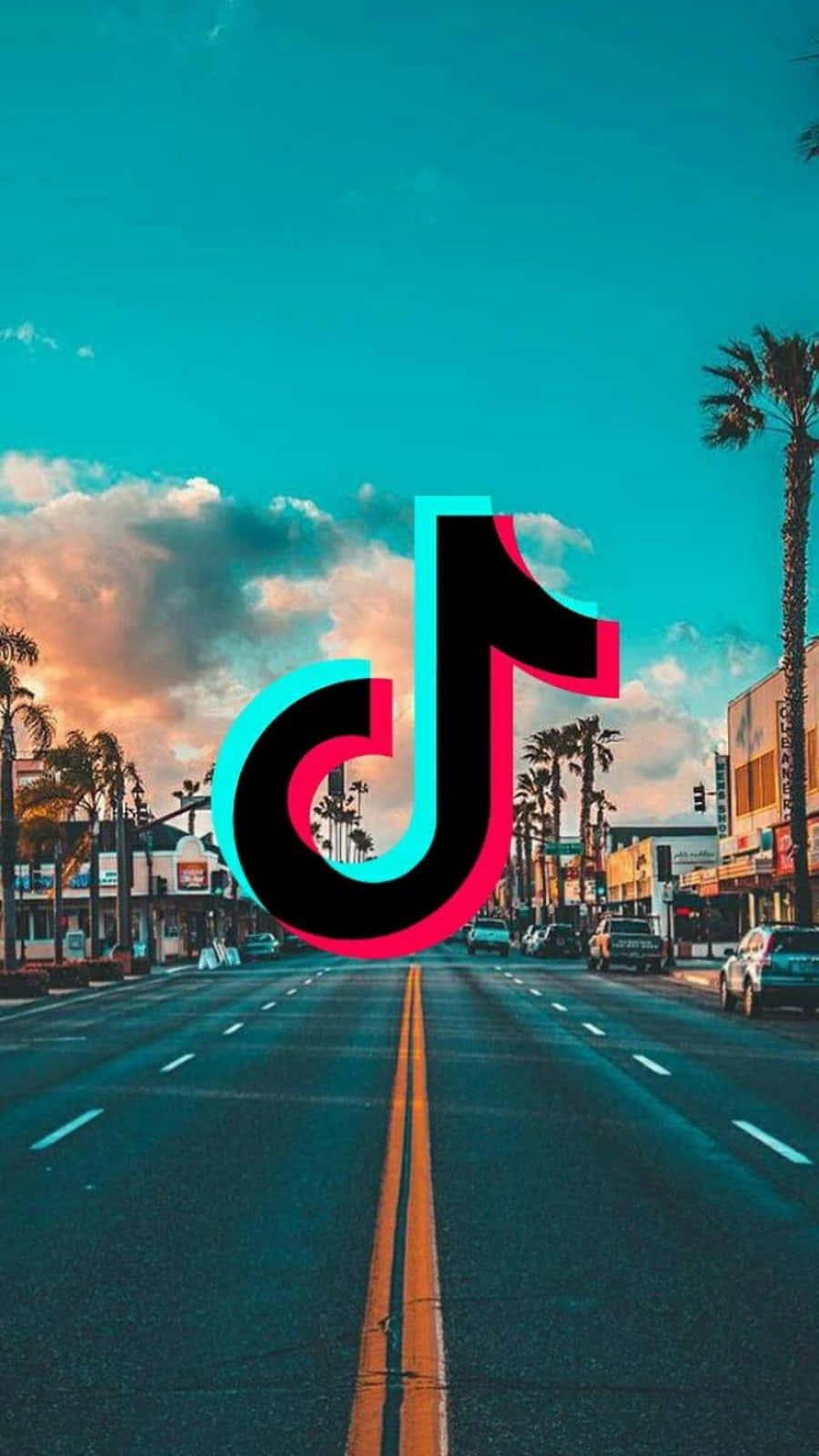 被聽見、展現創意、與世界連結——就在TikTok！ 壁紙 — TikTok 標誌漂浮在日落時分的棕櫚樹街道上，帶有充滿活力的藍綠色和粉紅色調。