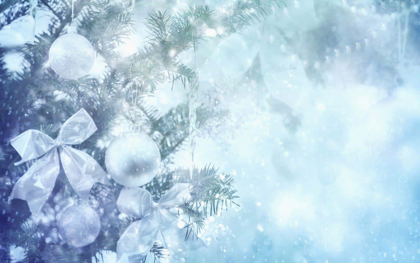 Snowy Christmas 桌布 壁紙 — 被雪覆蓋的聖誕樹枝條上裝飾著銀色飾品和蝴蝶結，在冰藍色背景上柔和地閃耀。