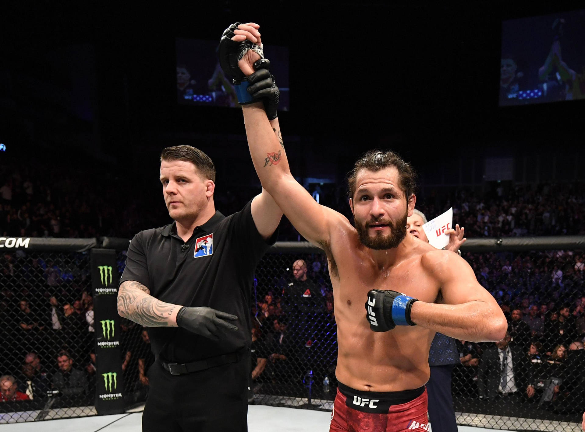 UFC拳手在八角籠內由裁判舉起手慶祝勝利。