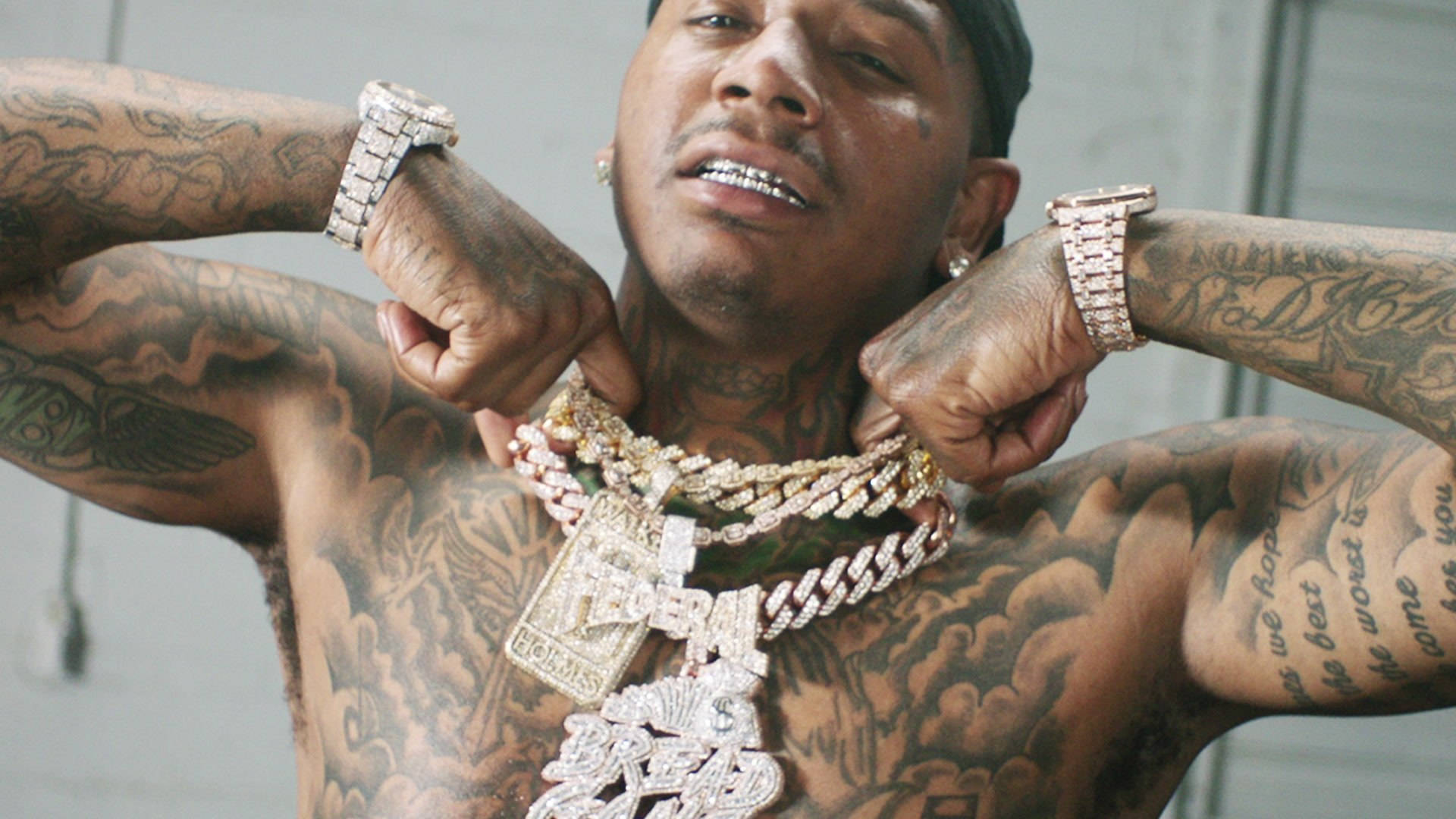 裸上身 Moneybagg Yo 壁紙 — 一名紋身男子彎曲手臂，展示多條鑲鑽鏈條和奢華手錶。