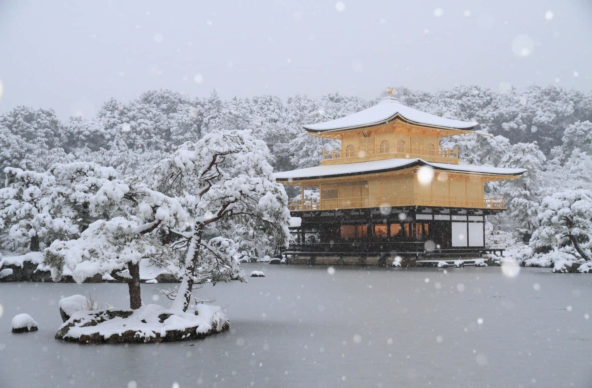 金色寺廟被雪覆蓋，旁邊是結冰的湖泊和積雪的樹木。