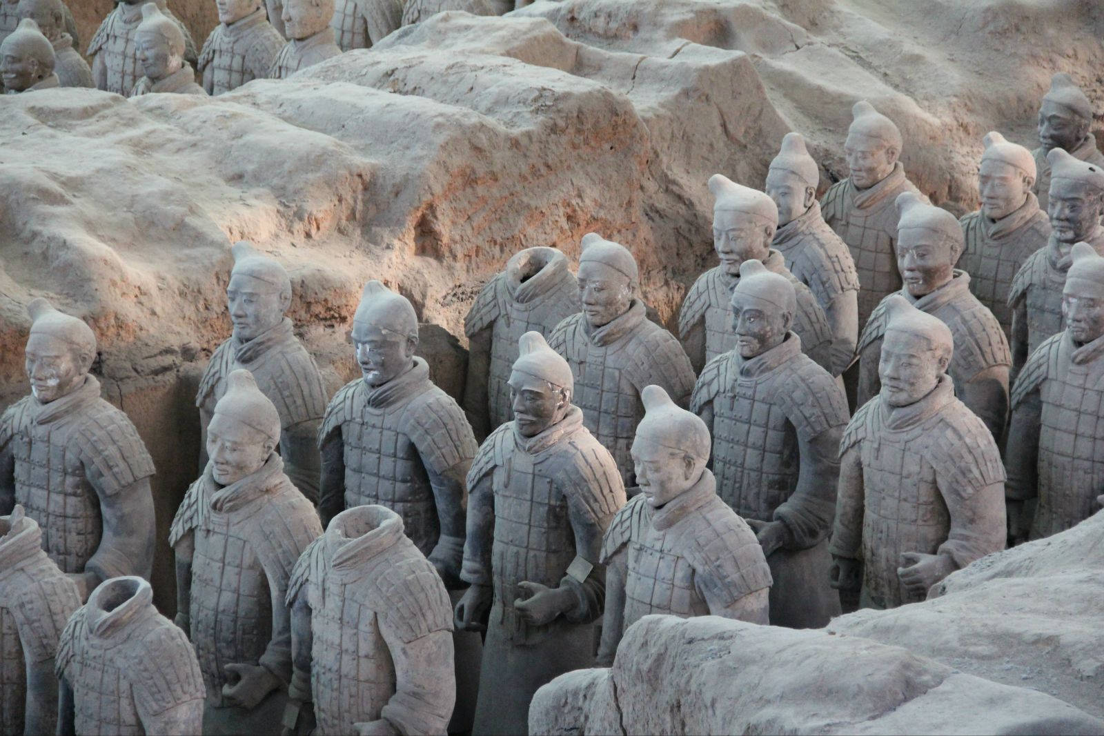 西安中國古雕像 壁紙 — 一排排古老的兵馬俑莊嚴地站在他們的發掘坑中，帶有大地色調和詳細的盔甲。