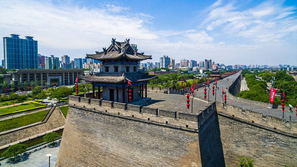 西安城牆與城市景觀 壁紙 — 古老的石城牆帶有傳統塔樓和紅色燈籠，在明亮的藍天下延伸至現代摩天大樓旁。