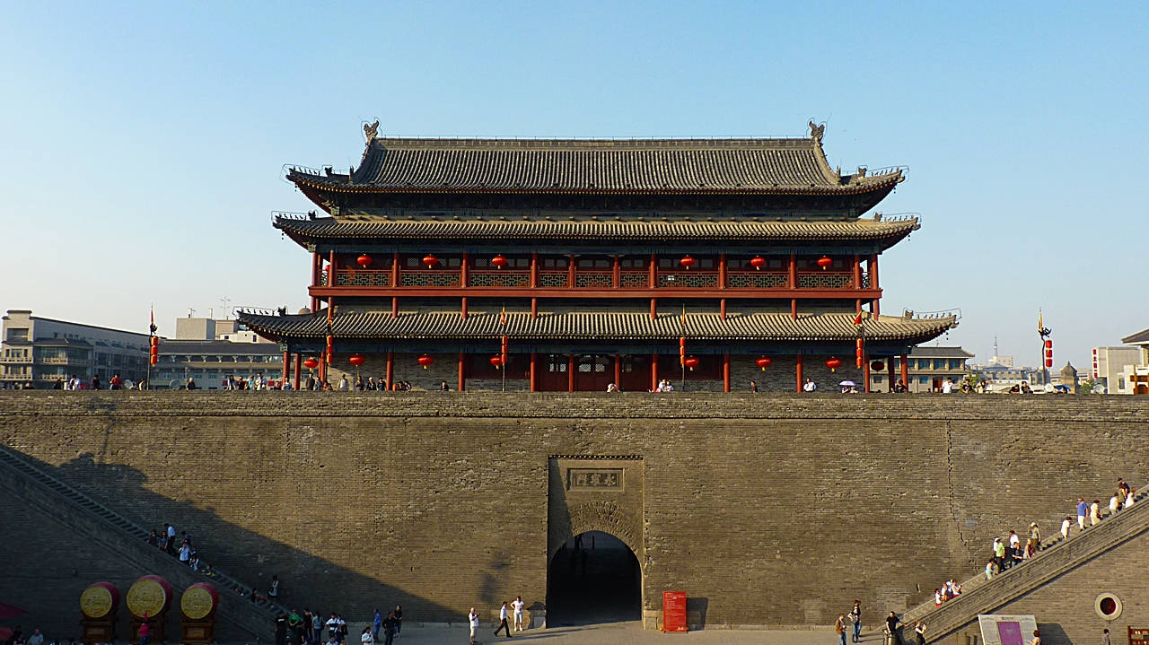 西安石牆大門 壁紙 — 宏偉的傳統中式門樓，掛著紅燈籠，矗立在古老的石牆上，天空湛藍清澈。
