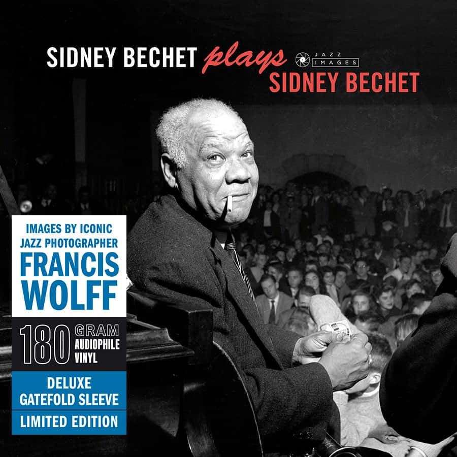 西德尼·貝切特演奏薩克斯風——專輯封面 壁紙 — Sidney Bechet 在黑白照片中微笑著在擠滿爵士俱樂部觀眾的舞台上演奏高音薩克斯風。