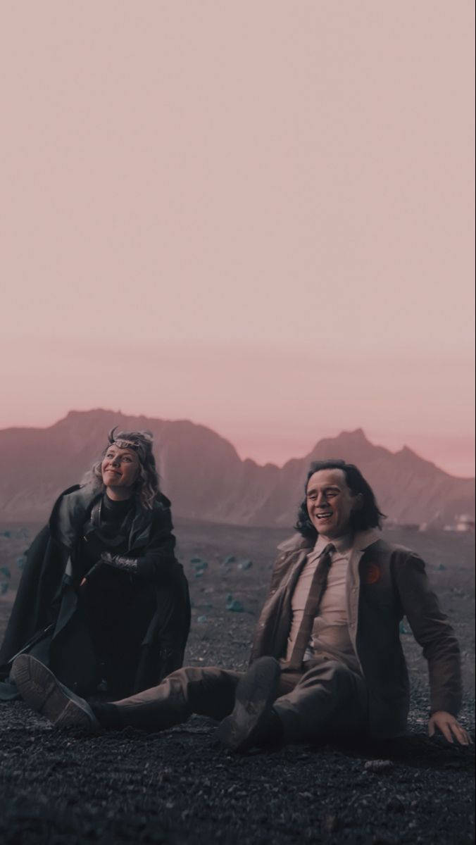 西爾維與洛基經典雙人組合 壁紙 — 兩個洛基變體坐在火山平原上，在粉紅色暮色天空下大笑，遠處有鋸齒狀的山脈。