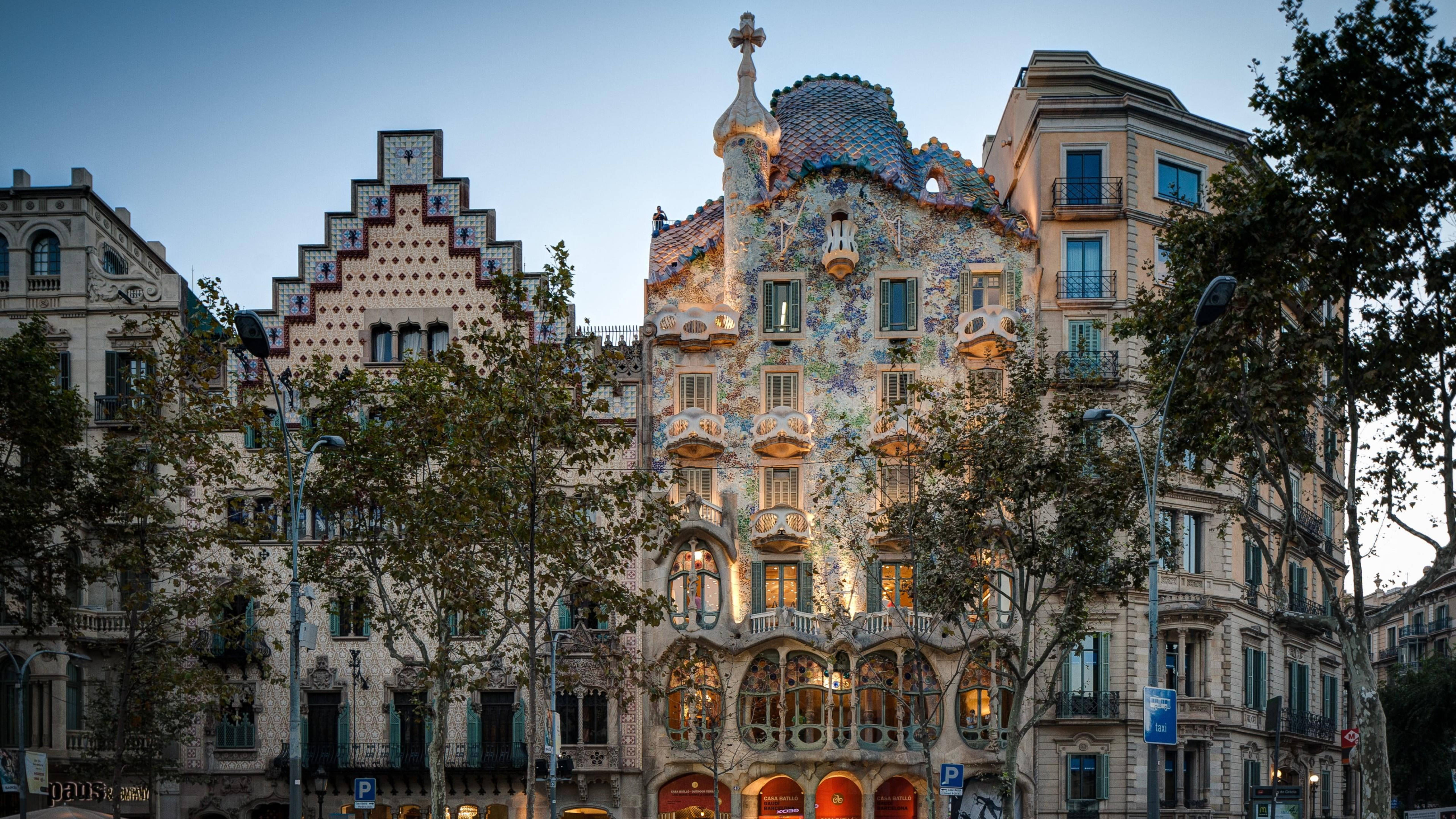 西班牙巴塞羅那高迪設計的巴特略之家 壁紙 — 巴塞隆拿 Casa Batlló 的迷人黃昏景色，其馬賽克外牆在柔和藍天下溫暖地發光。
