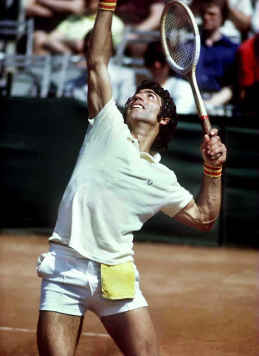 西班牙網球選手曼努艾爾·奧蘭特斯於1975年美國公開賽四強賽 壁紙 — 一名身穿白色球衣的男網球手在明亮的日光下於泥地球場上執行強力的過頭扣殺。