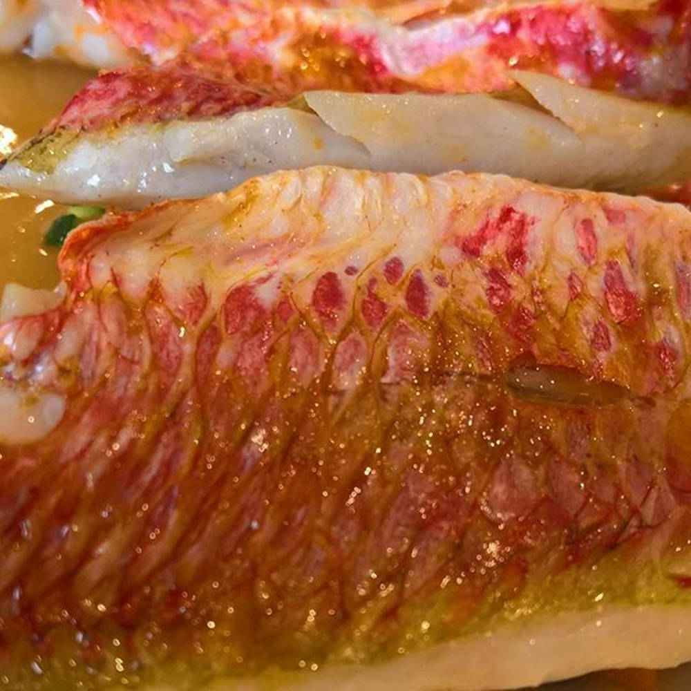 切片烤魚柳帶粉紅色大理石紋理及閃亮醬汁。