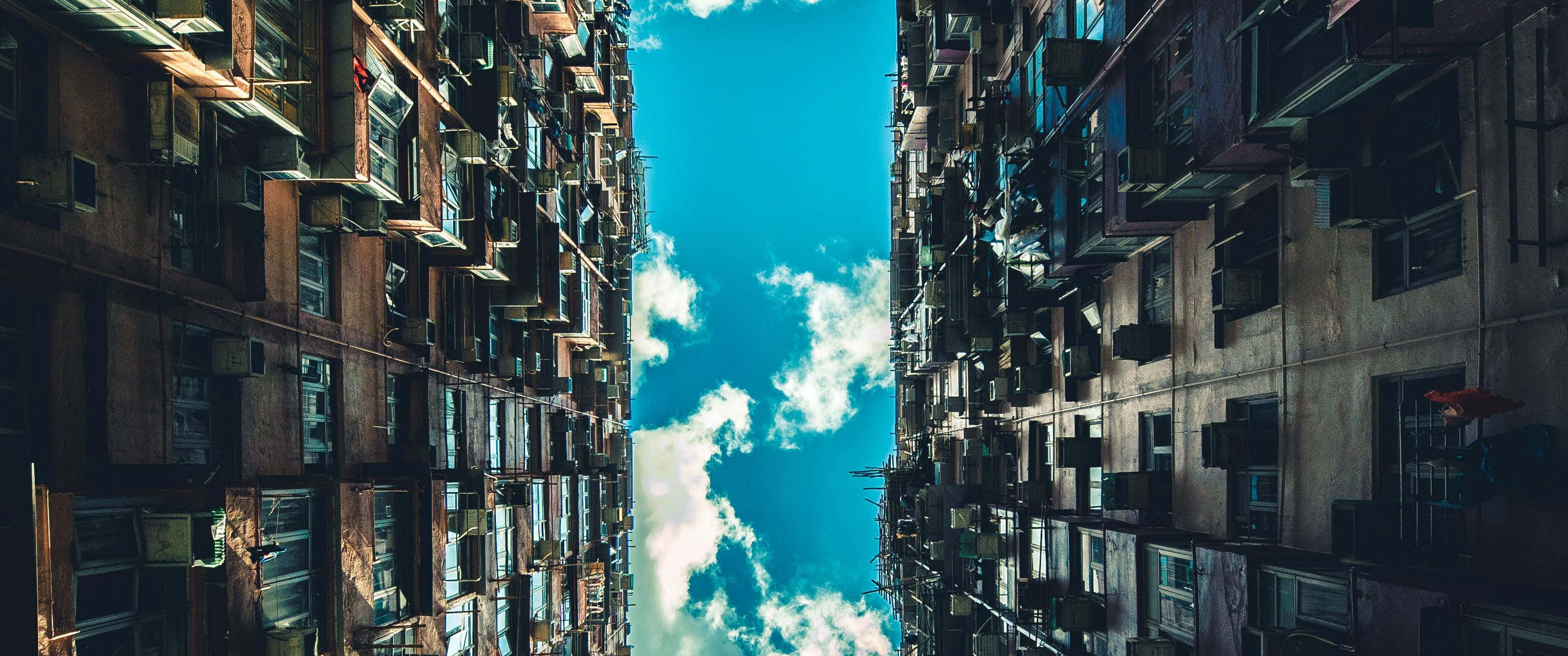 西雅圖日落時分 壁紙 — 高聳的都市公寓大樓以戲劇性的低角度構圖，框住一片充滿活力的藍天和蓬鬆的白雲。