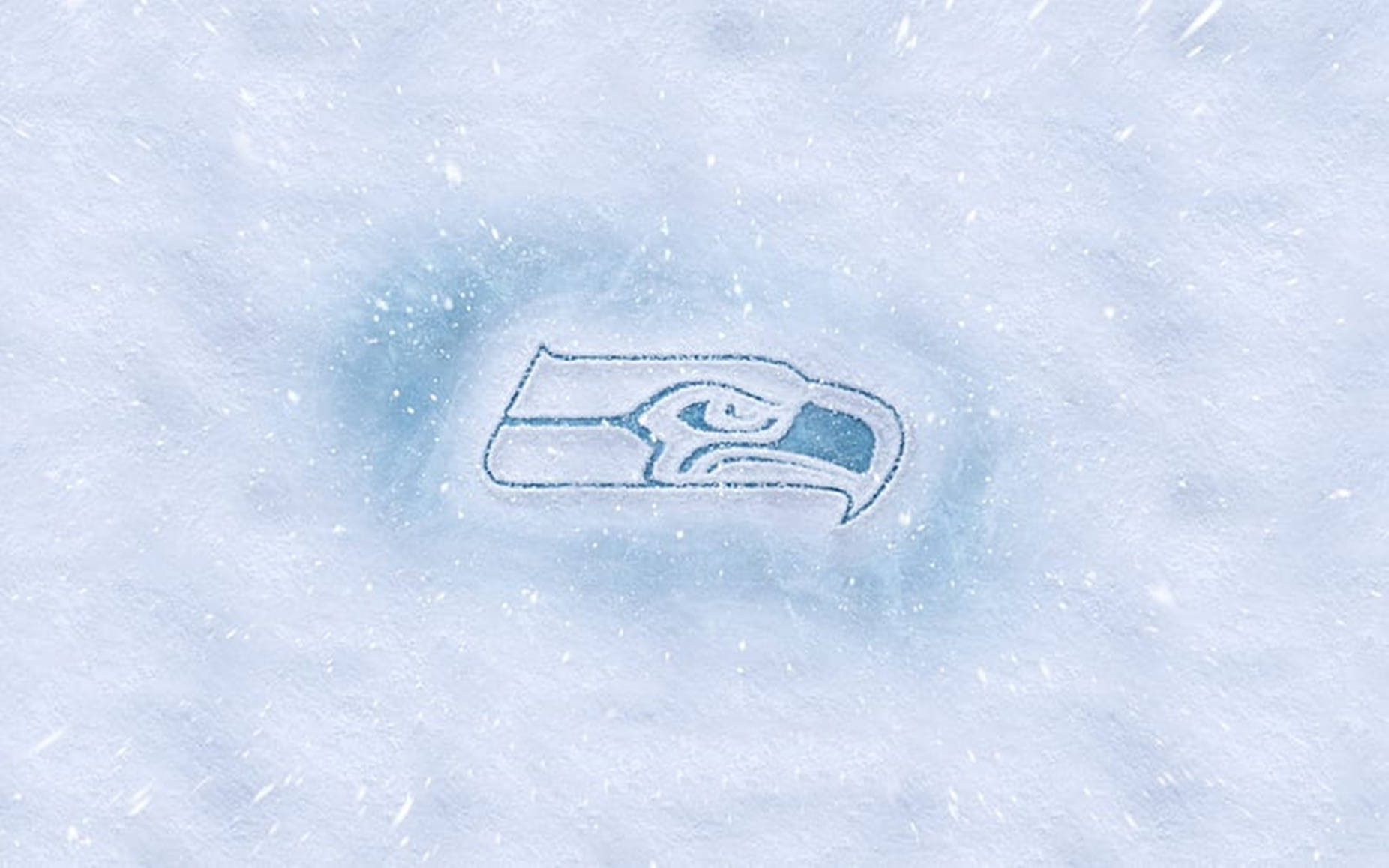 Seattle Seahawks 桌布 壁紙 — 西雅圖海鷹隊標誌刻在雪中，飄落的雪花在其冰冷輪廓周圍旋轉。